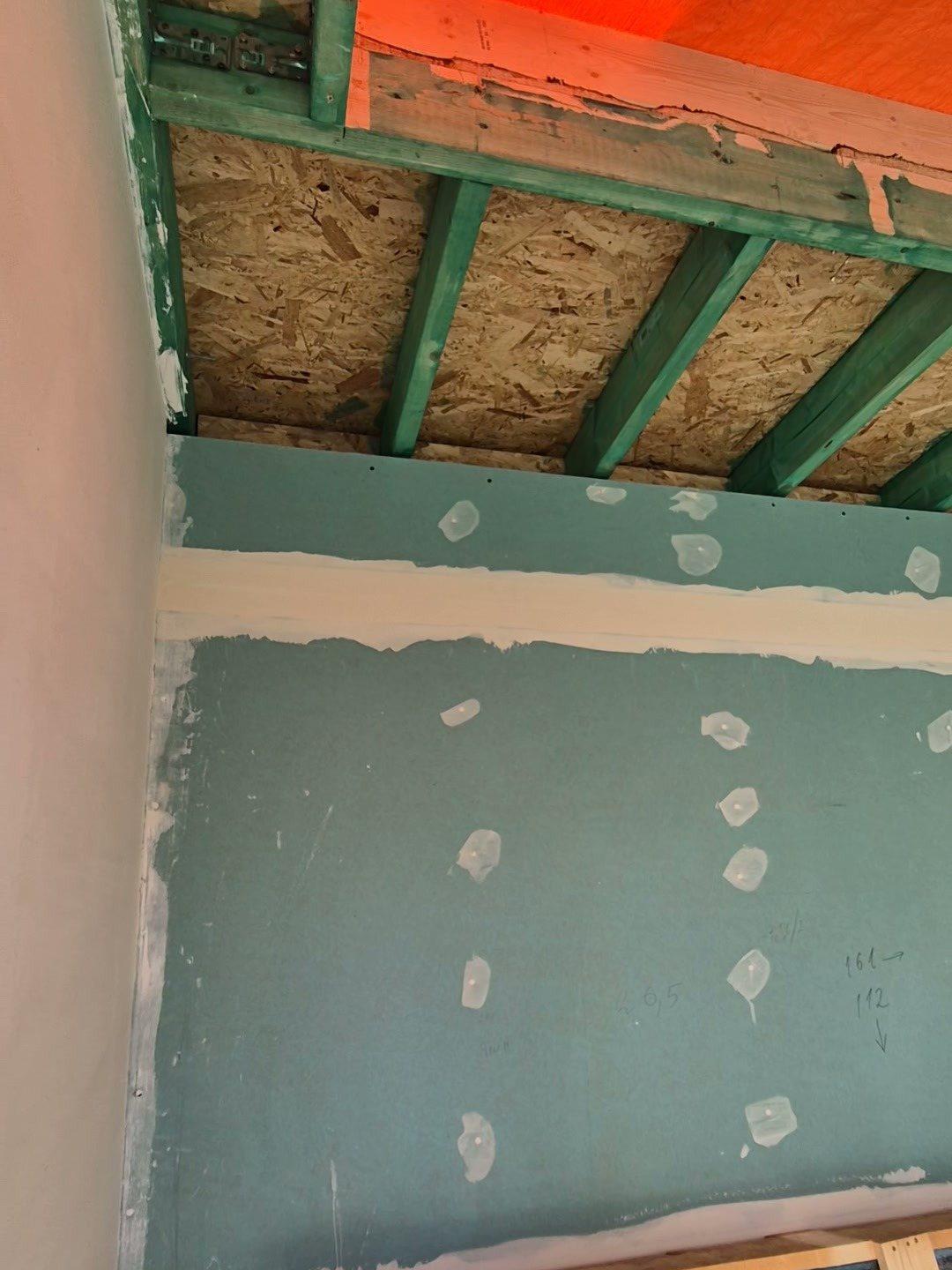 Plat dak van de entreeaanbouw van binnenuit: groen geïmpregneerde balken, OSB-dakplaten en gipsplaat op de wand (in uitvoering).