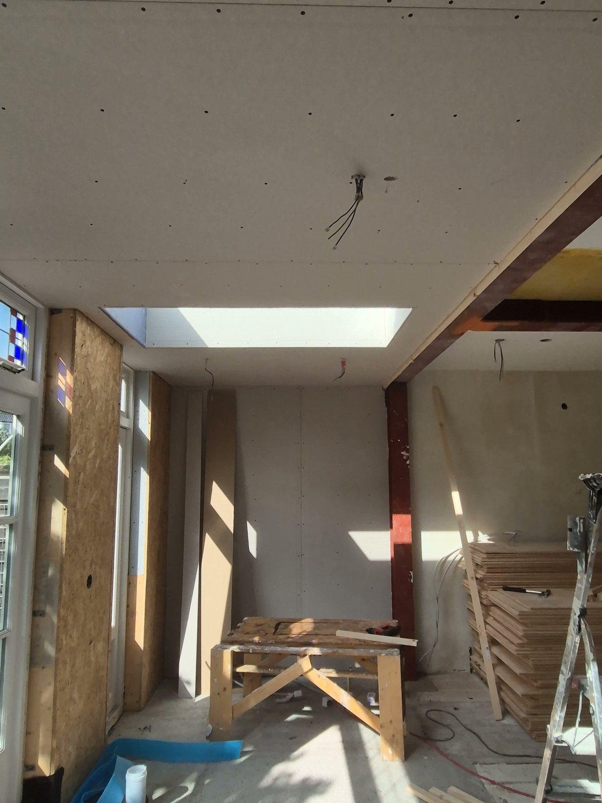 Ruwbouw van een uitbouw: een roodgegronde stalen kolom en balk waar de oude achtergevel is geopend, OSB-wanden en een daklicht in het nieuwe plafond (in uitvoering).