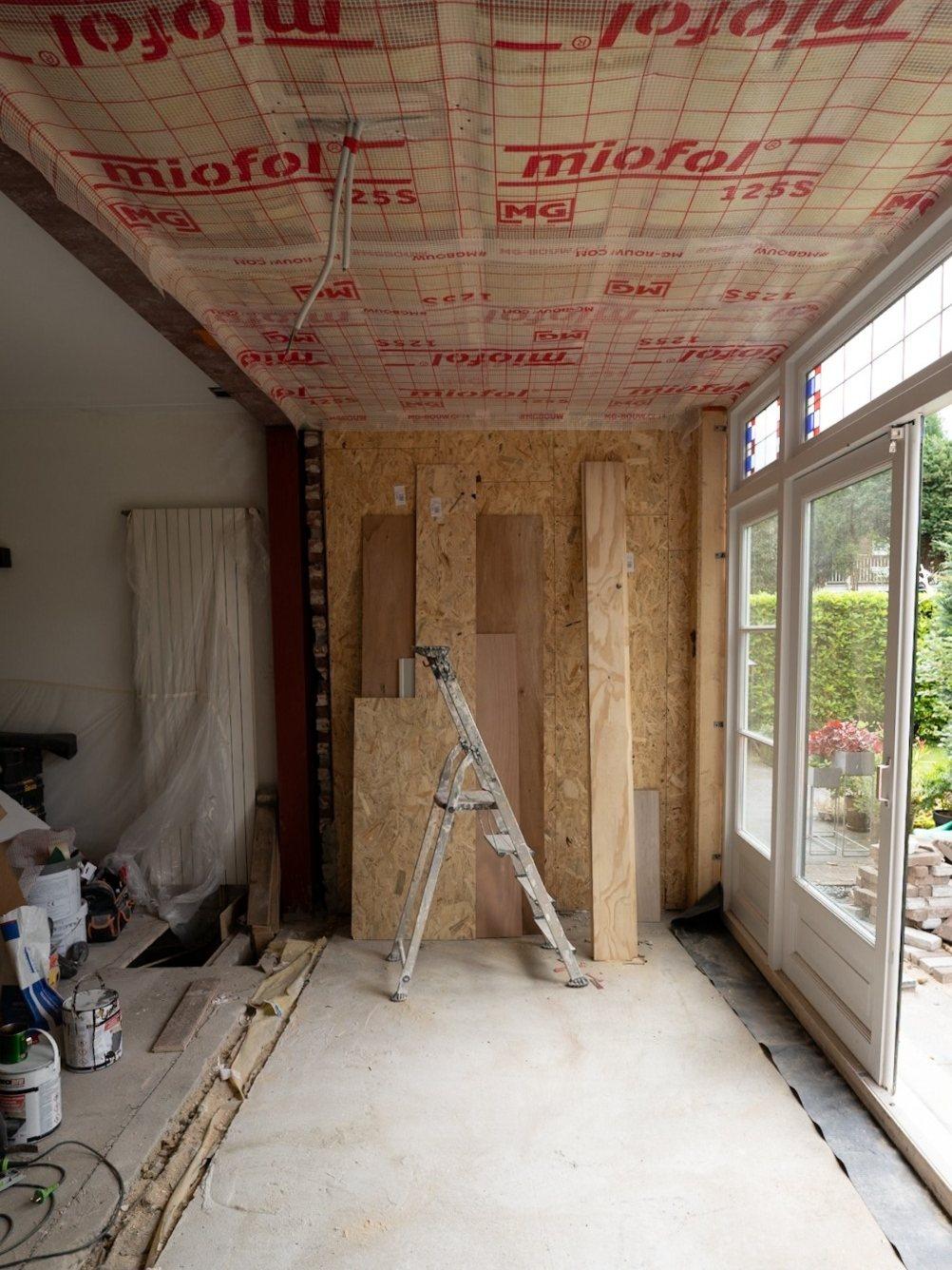 Dampremmende folie op het plafond, OSB-platen op de eindwand en tuindeuren rechts in een uitbouw (in uitvoering).