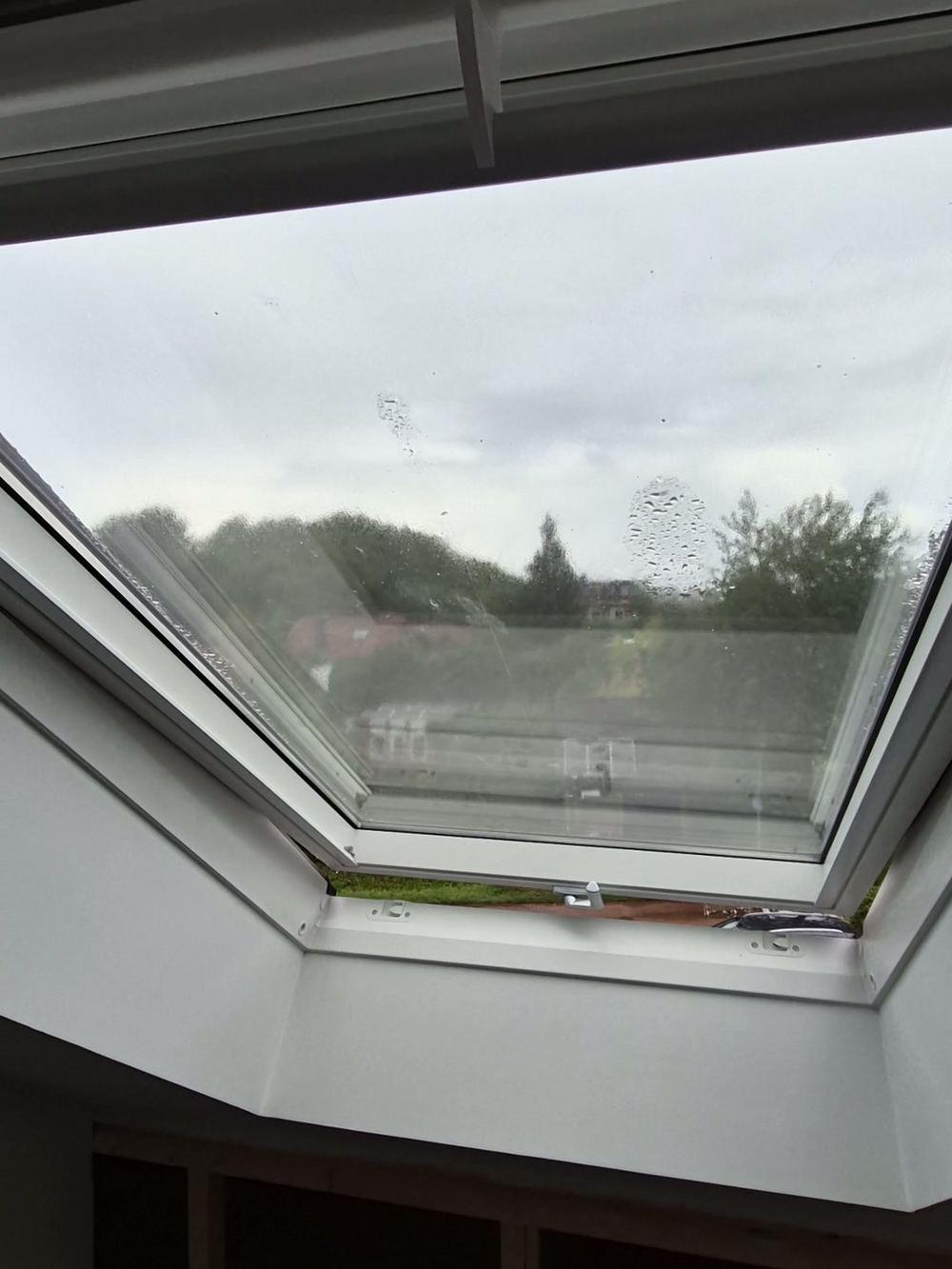 Open roof window with a white lining in the roof slope, before the room below is finished (in progress).