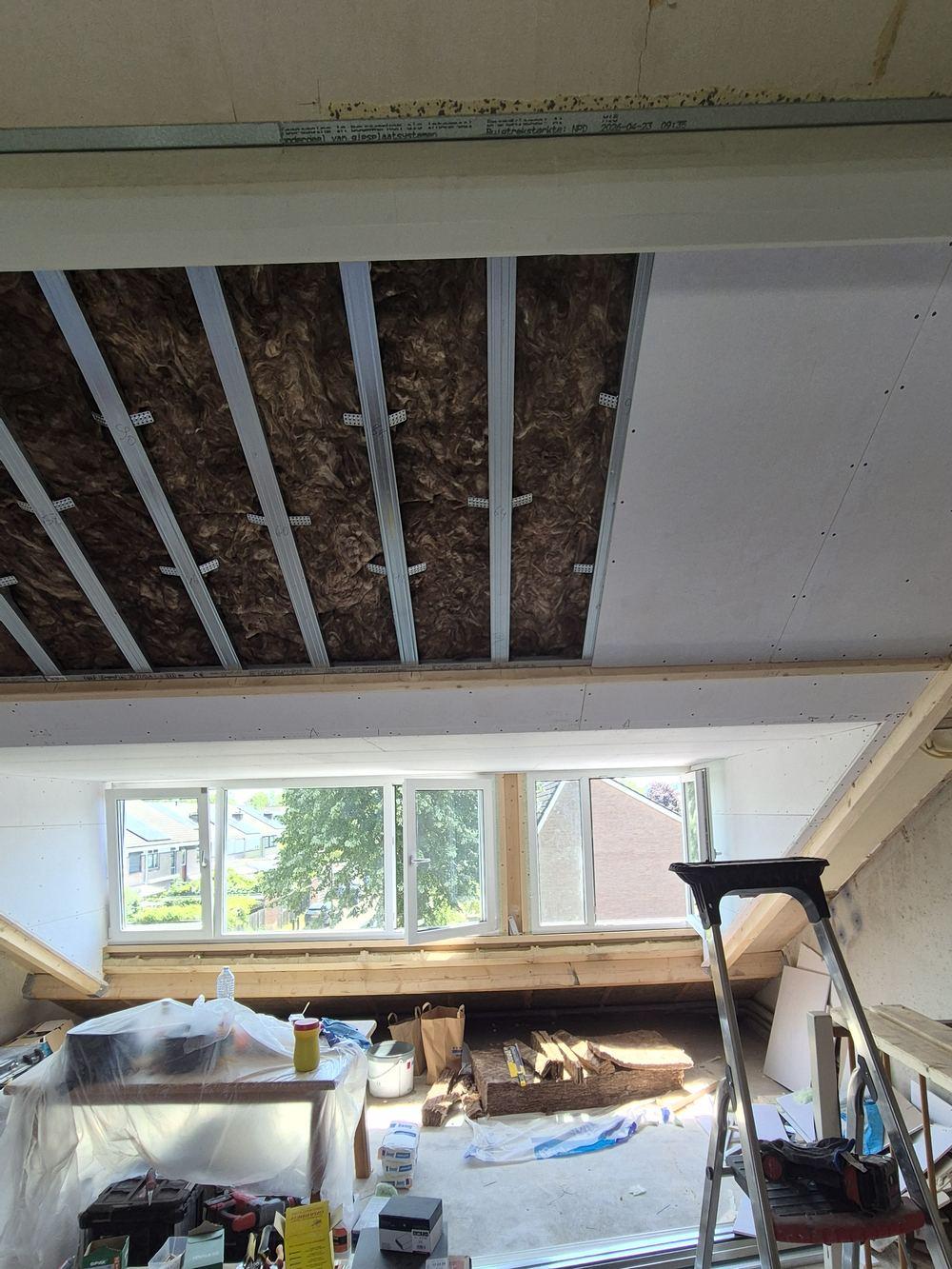 Mineral wool insulation between metal profiles on the roof slope, with the dormer windows in the background (in progress).