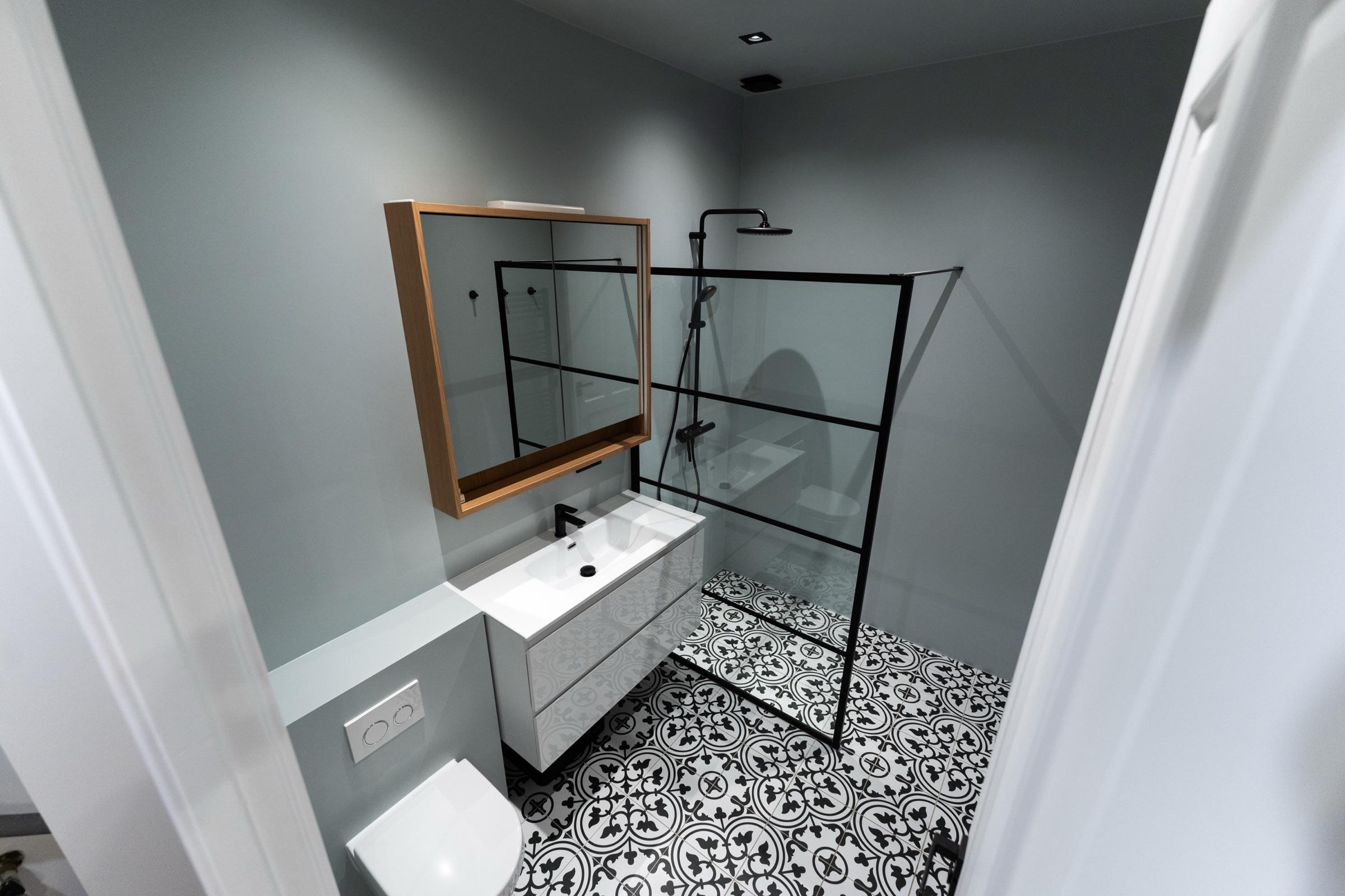 Compacte badkamer met inloopdouche in zwart profiel en zwart-wit gepatroneerde vloertegels