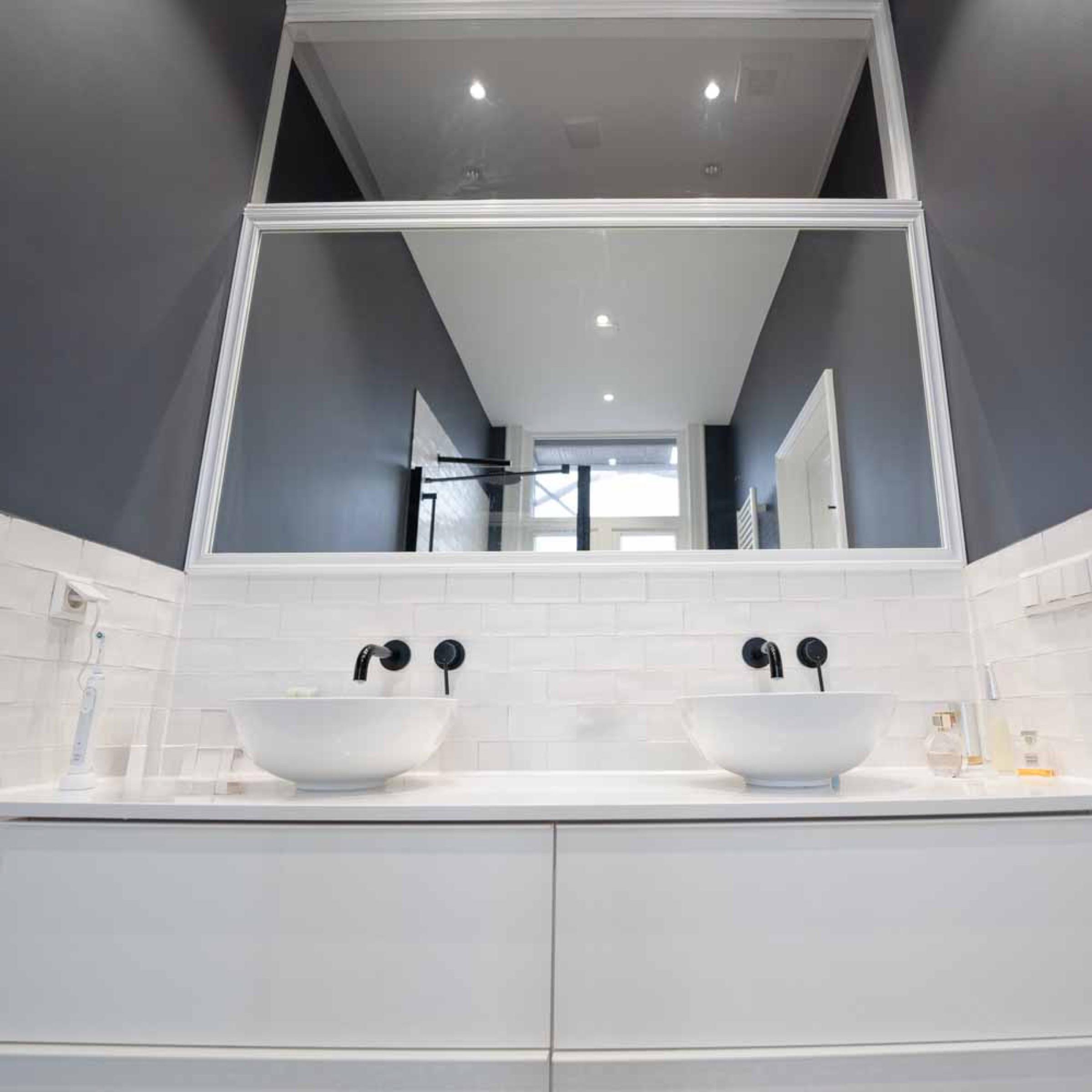 Double vanity with two white countertop basins, black wall taps and white metro tiles