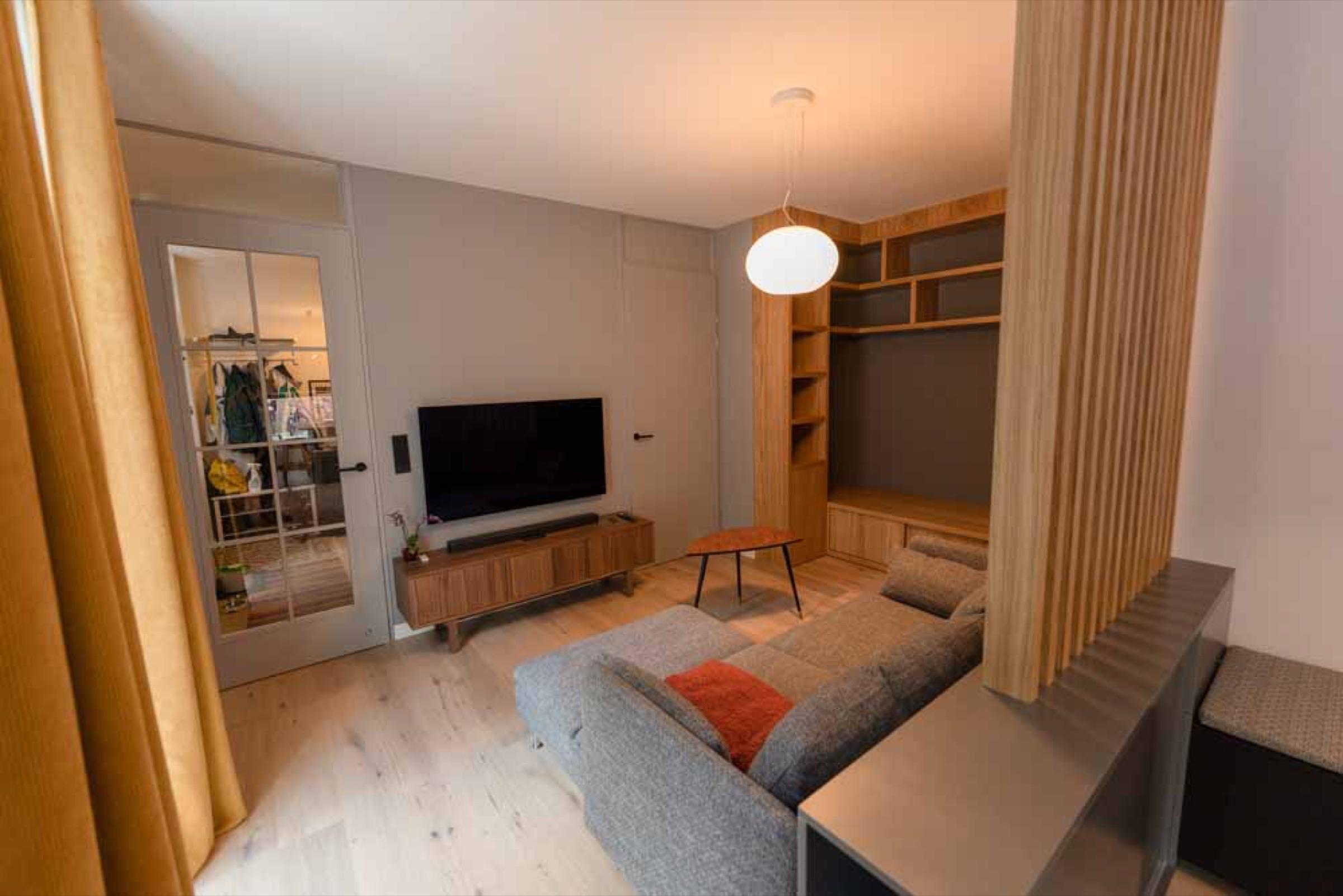 Living room with wall-mounted TV, walnut sideboard and glazed panelled door to a dressing room